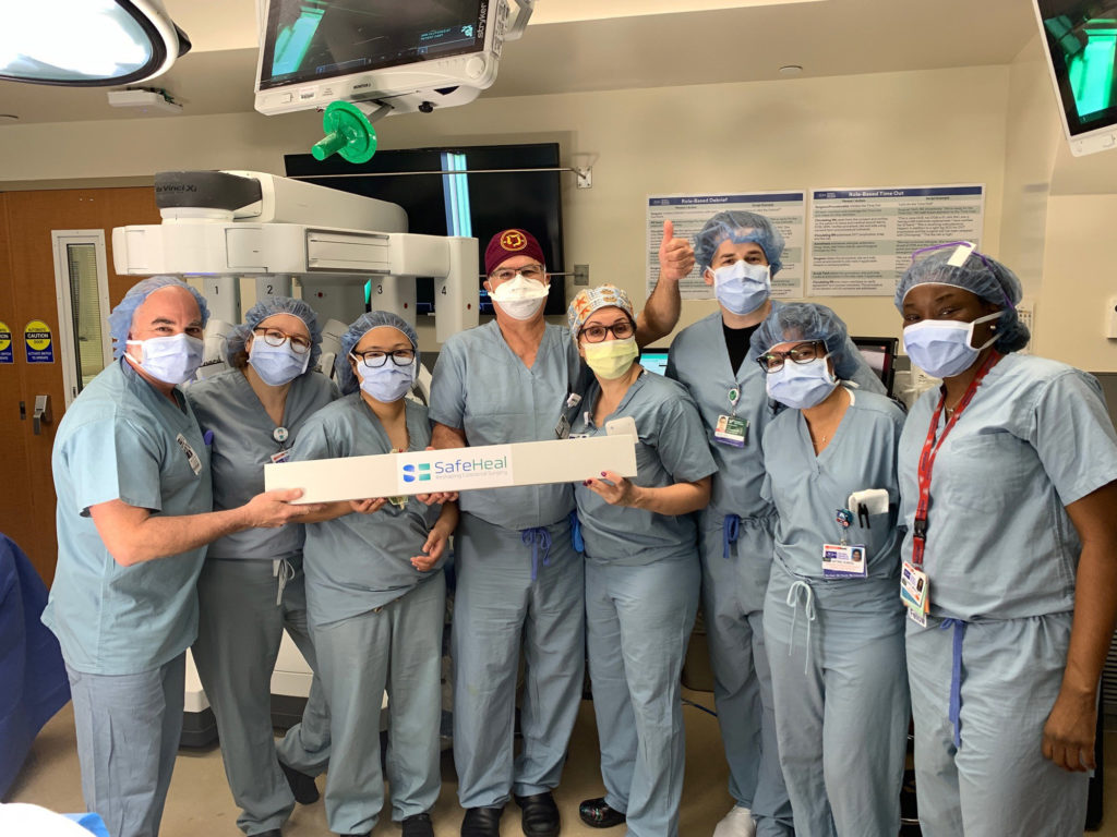 A group of surgeons gather in the operating room with masks on their faces