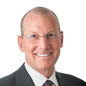 A man smiles in front of a white back drop.